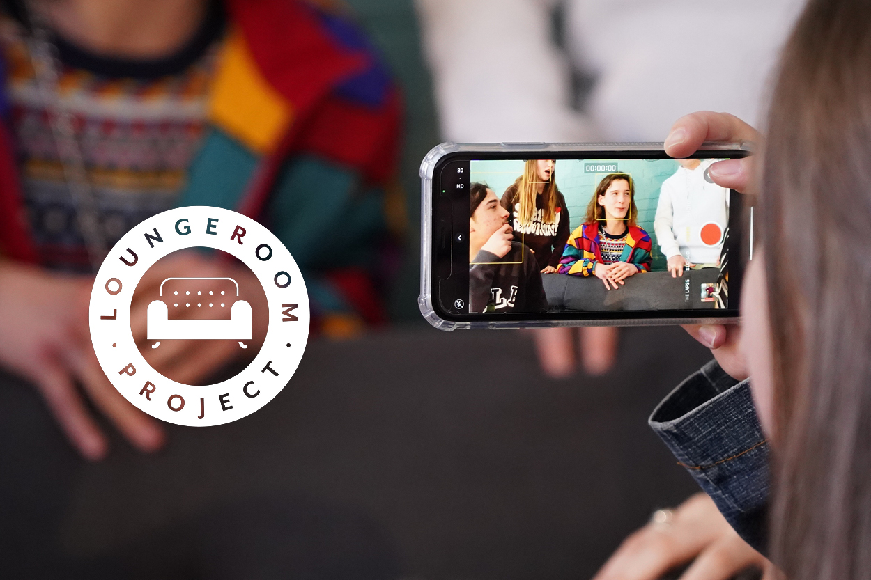 On left is Loungeroom Project logo, on the right young female holds iphone displaying image of her friends in various poses